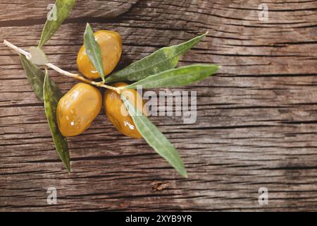 Top view of appetizing marinated green olives and olive branch on wooden background Stock Photo