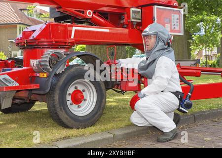 Work Men Insect Insect killer in protective working clothes operates aerial platform ...