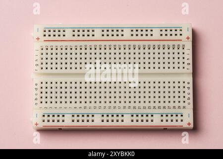 An electronics breadboard on pink background Stock Photo