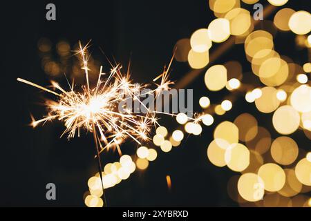 Sparklers on blurred christmas lights. Festive mood. Stock Photo