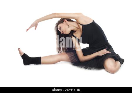 Female ballet dancer in black dress doing exercises on white background Stock Photo