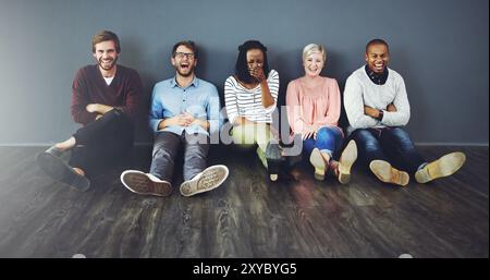 Portrait, diverse and laughing on floor, friends and bonding of colleagues with joke, creative and group. Comedy, music producer and person with Stock Photo
