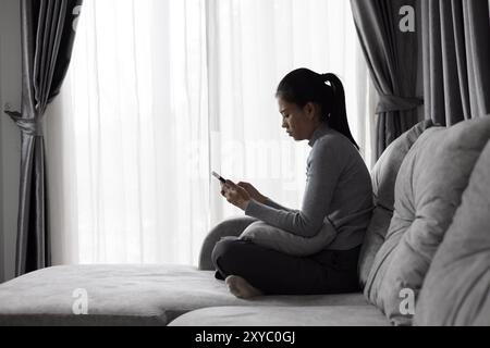 Depressed woman, person sitting alone on the sofa felling sad worry. Stress, suicidal thoughts. Stock Photo