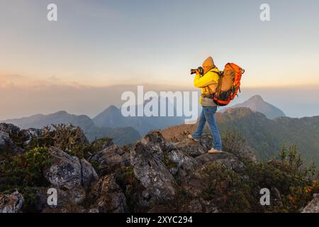 Nature Photography Concept. Professional Nature Professional Nature Photographer taking photos on top mountains sunset background.  Hiking, taking pho Stock Photo