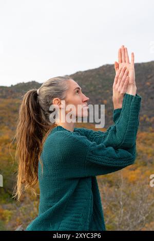 Caucasian middle-aged woman with long hair doing yoga and meditation outdoors in an autumn landscape Stock Photo