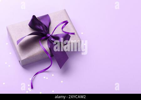 Vintage gift box with purple ribbon and golden confetti on pink background copy space Stock Photo