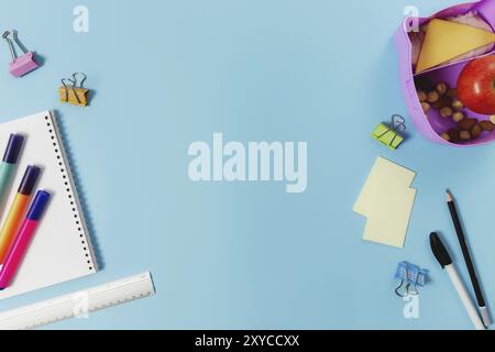 Primary school flat lay concept with assorted school supplies, notepad, pen, pencil, markets, stickers, paper clips and lunch box with sandwich, nuts Stock Photo