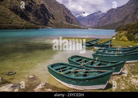 Huaraz, PERU in November 2015: Six green boats are waiting to be sailed across the blue glacier lagoon in the Peruvian Andes. Huaraz is a popular tour Stock Photo