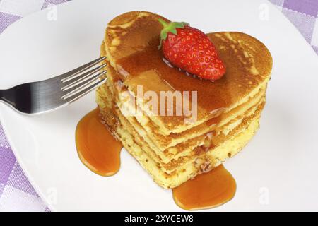 Heart-shaped pancakes with syrup and a strawberry on a white dish. A perfect breakfast for Valentine's Day Stock Photo