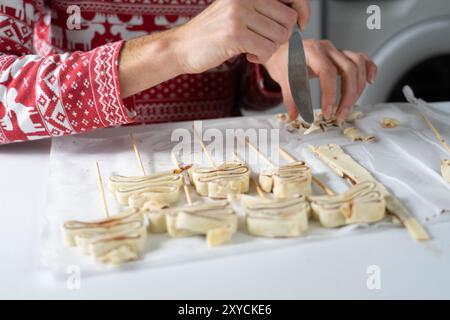 Woman's hands dressed in a Christmas t-shirt cooking some Christmas sweets in the shape of Christmas trees Stock Photo