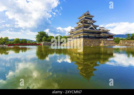 Clouds in a blue summer sky and the keep of Matsumoto Castle is reflected beautifully in moat water in Nagano Prefecture, Japan. Horizontal Stock Photo