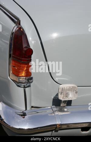 A vintage car tail light illuminates a cobbled street, embodying