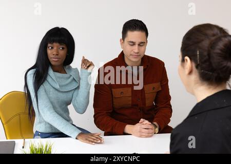 Young couple is discussing with a financial advisor at her office desk Stock Photo