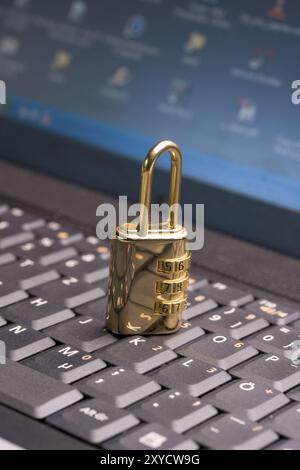 A golden padlock on a black notebook keyboard Stock Photo