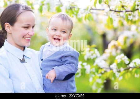 Little baby boy with his young mother in the blossoming spring garden Stock Photo