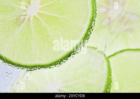 Slices of fresh lime floating in sparkling water Stock Photo