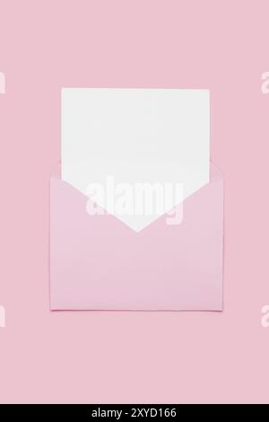 Closeup on blank empty white paper card in pink opened envelope isolated on pink pastel color background. Love letter minimal concept. Conceptual layo Stock Photo
