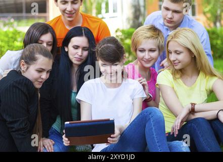 Young college students using tablet computer while doing homework in the park Stock Photo