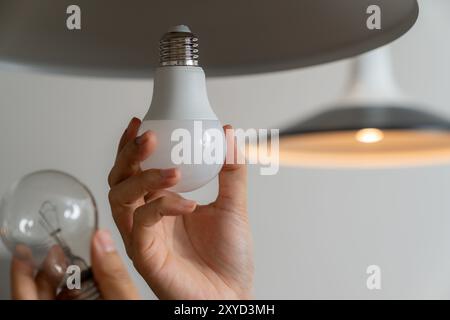 The young woman is replacing the incandescent bulb with an LED bulb Stock Photo