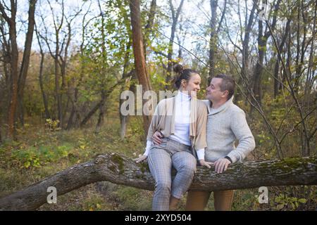 Beautiful couple sitting together on the tree in park hugging Stock Photo