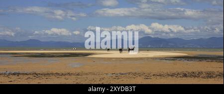 Sandy Marahau beach at low tide. Clouds over a mountain range. Idyllic scene in New Zealand Stock Photo