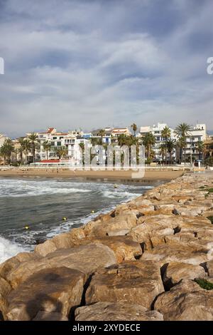 Sitges, resort town in Spain, skyline from sea pier made with boulder rocks Stock Photo