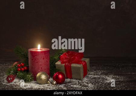 Red candle gift box with ribbon christmas new year decorations on snow dark background Stock Photo