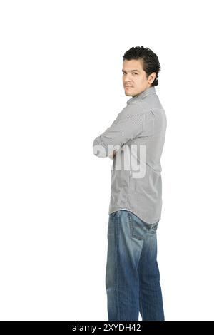 Rear view of reserved hispanic man wearning casual clothes arms crossed looking behind at camera over his shoulder showing facial expression of stern, Stock Photo