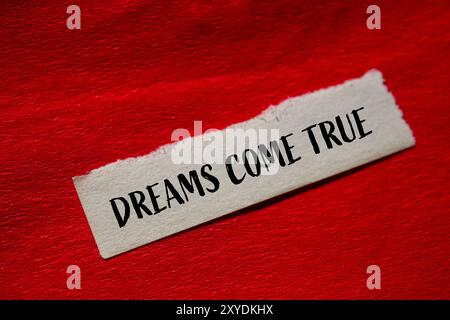 Dreams come true message written on ripped torn paper piece with pink ...
