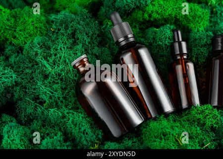 Brown glass dropper bottles arranged on green moss in a natural setting Stock Photo