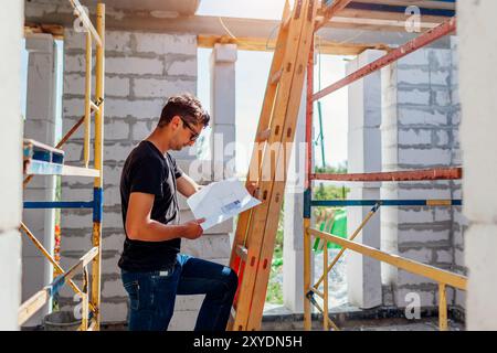 Man architect engineer checking house under construction comparing with blueprint plan on paper. Gas block Stock Photo