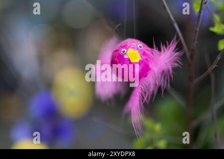 Easter decoration. A pink Easter egg in the shape of a bird hangs from a bush with green leaves Stock Photo