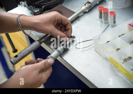 Men's hands measure a micrometer special compression washers to adjust diesel injectors. Close-up Stock Photo