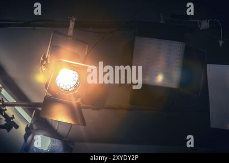 Professional orange studio spotlight hanging on the ceiling Stock Photo