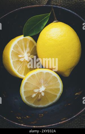 Fresh lemons in a bowl on dark wood background Stock Photo
