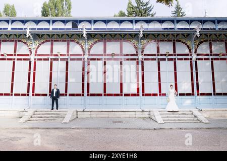 Newly-weds are standing separately on the background of the old exhibition gallery on different edges of the frame The concept of a wedding walk and f Stock Photo
