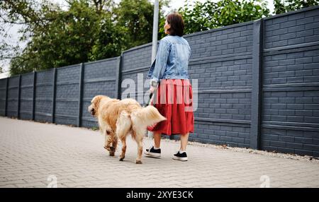 Girl Walks With Dog Along A Calm Street Stock Photo