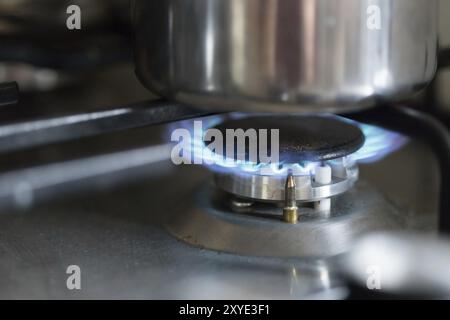 Close up of a blue gas flame, cooking a water pot in kitchen Stock Photo