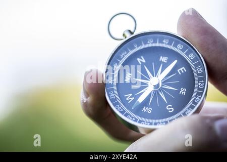 Young man on an adventure is holding a compass in his hand for finding is route Stock Photo