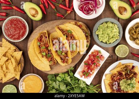 An overhead photo of an ssortment of many different Mexican tapas, including tacos, guacamole, pico de gallo, nachos and others Stock Photo