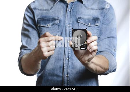 Man's hand holds a 2.5 inch hard drive. He's points to the hard disk. View of the backside HDD, from the PCB. Isolated on white background Stock Photo