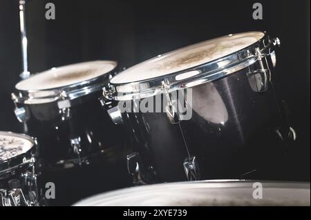 Closeup view of a drum set in a dark studio. Black drum barrels with chrome trim. The concept of live performances Stock Photo