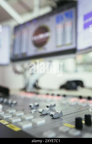 Close up picture of a soundboard in a broadcasting studio, computers in the blurry background Stock Photo