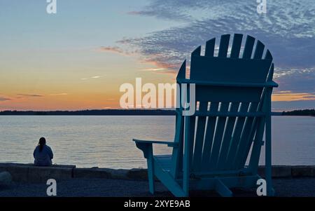 A woman sits on the edge of the beach watching a late summer sunset a very relaxing setting Stock Photo