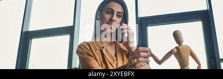 A Middle Eastern woman in a corporate setting talks on the phone while working. Stock Photo