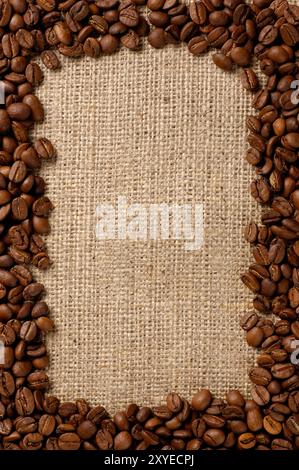 Vertical frame made from aromatic coffee beans on sacking fabric background Stock Photo