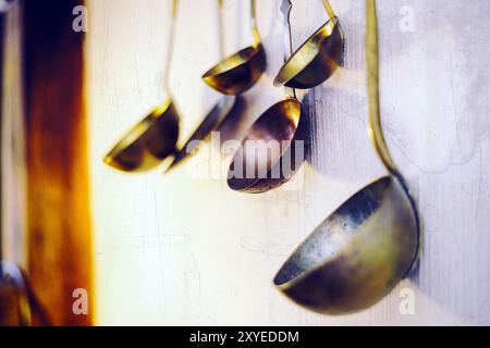 Soup ladles hanging on a white wall Stock Photo