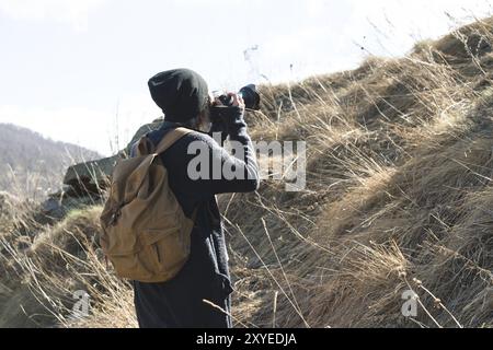 Woman hipster-photographer with dslr camera take pictures, Stylish girl in sunglasses with a camera on the nature Stock Photo