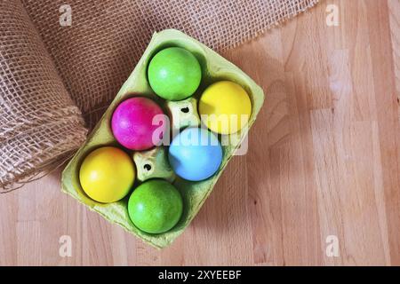 Brightly colored bow decorated easter eggs in egg carton holder, holiday background Stock Photo