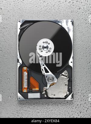 Open computer hard disk drive HDD on wet metal surface Stock Photo